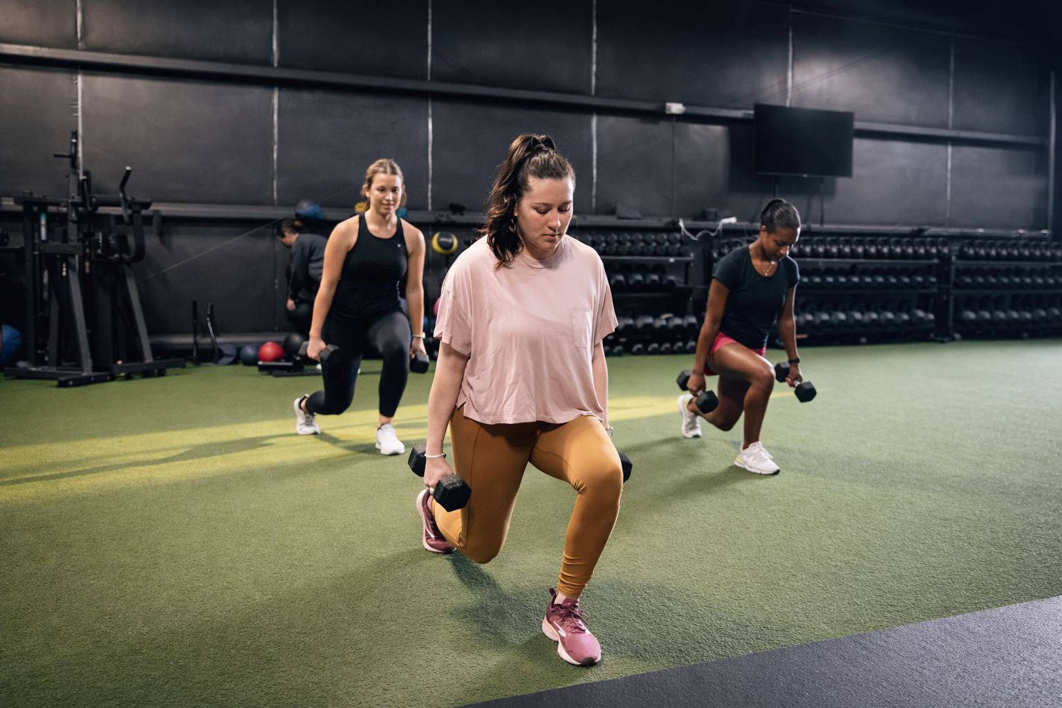 A group fitness class performing weighted lunges at The Studio 205