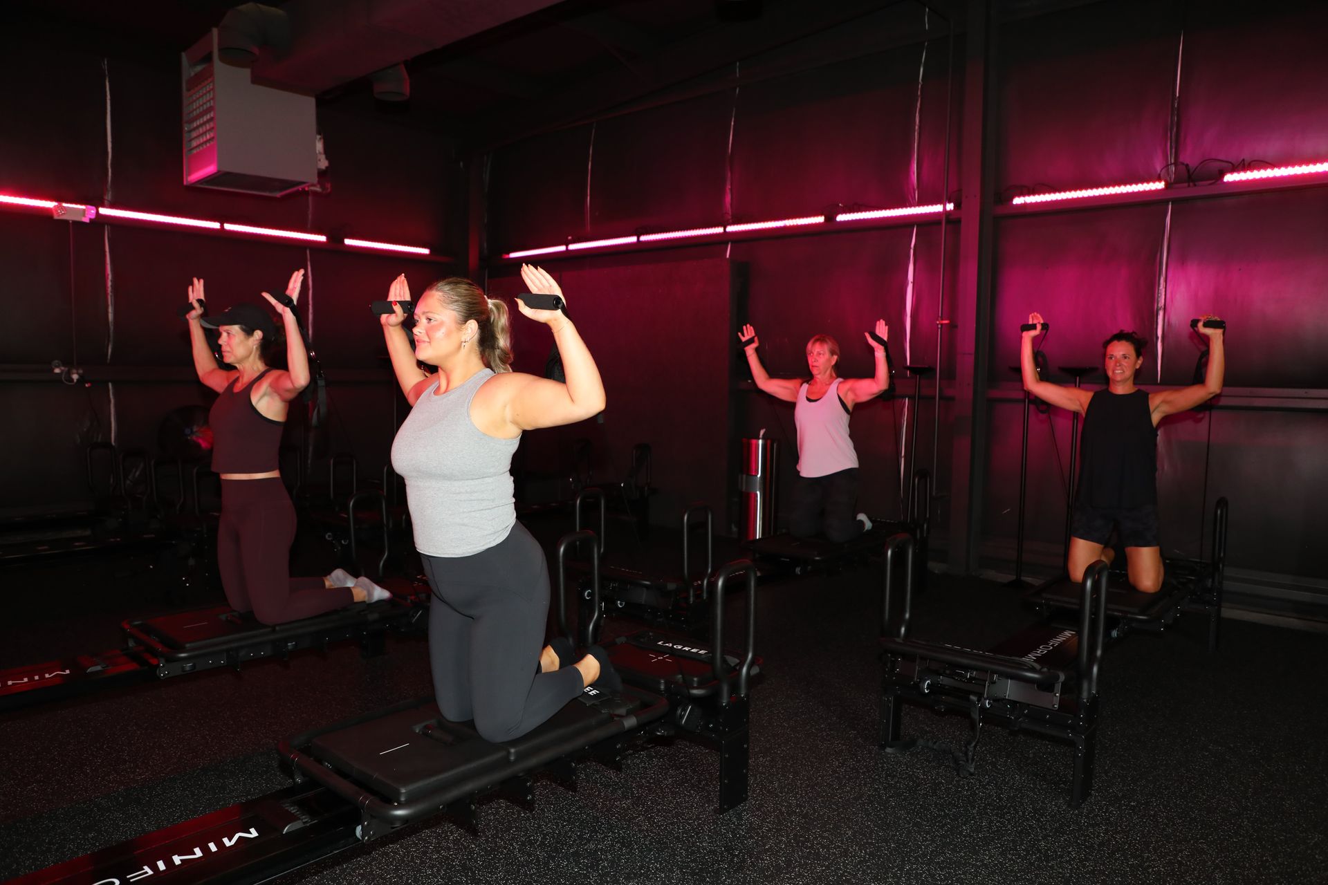 A Lagree Pilates group class at The Studio 205 under hot-pink neon lighting